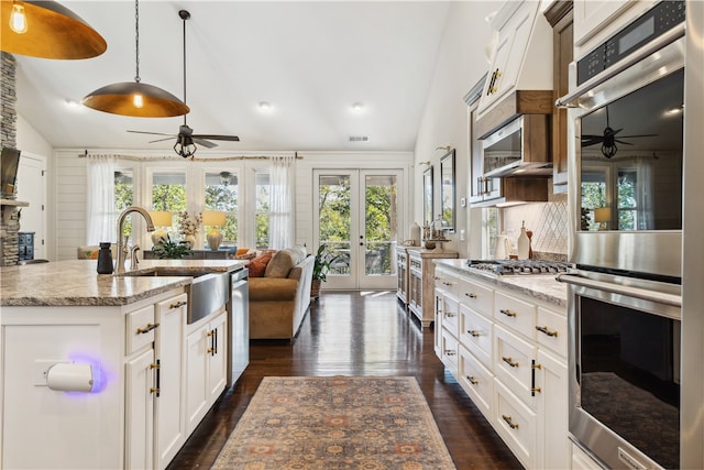 kitchen with french doors, appliances with stainless steel finishes, a kitchen island with sink, sink, and white cabinets