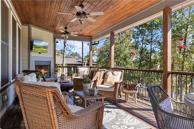 sunroom / solarium with ceiling fan, an outdoor fireplace, and wood ceiling