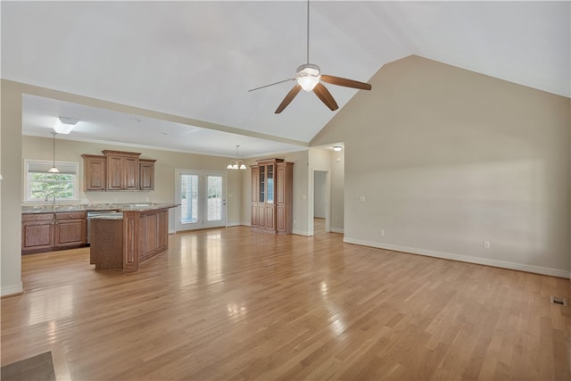 unfurnished living room featuring plenty of natural light, french doors, ceiling fan with notable chandelier, and light hardwood / wood-style flooring