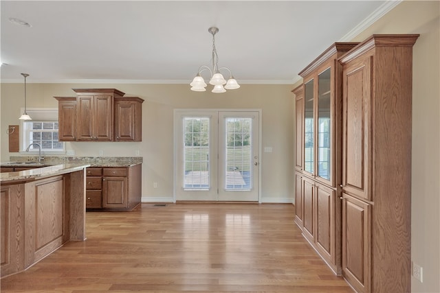 kitchen with a chandelier, light stone counters, pendant lighting, and light hardwood / wood-style floors