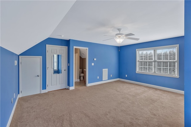 unfurnished bedroom featuring ceiling fan, light colored carpet, ensuite bathroom, and lofted ceiling