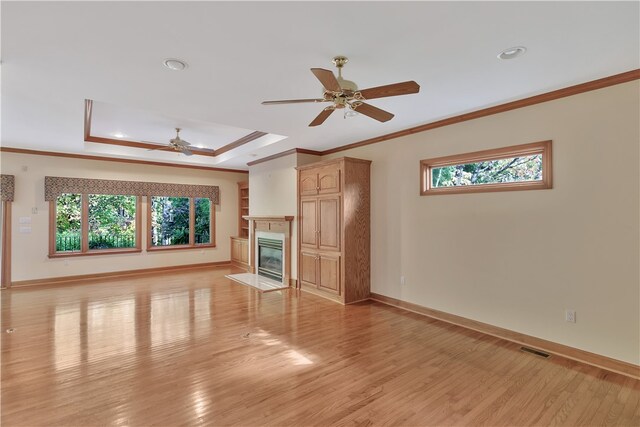 unfurnished living room featuring a high end fireplace, light wood-type flooring, ceiling fan, and crown molding