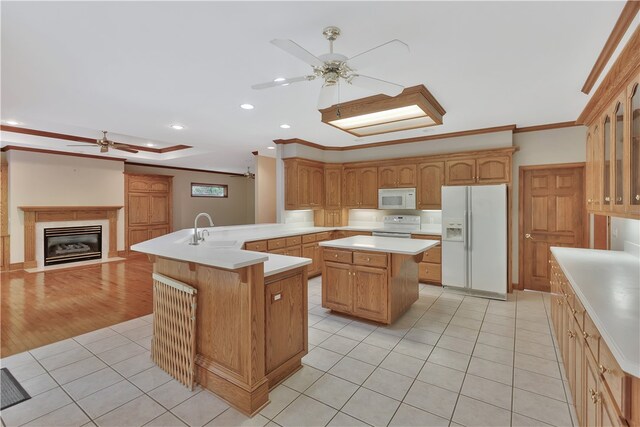 kitchen featuring kitchen peninsula, ornamental molding, white appliances, sink, and a kitchen island