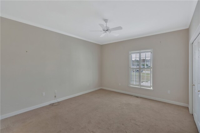 spare room featuring light colored carpet, ceiling fan, and crown molding