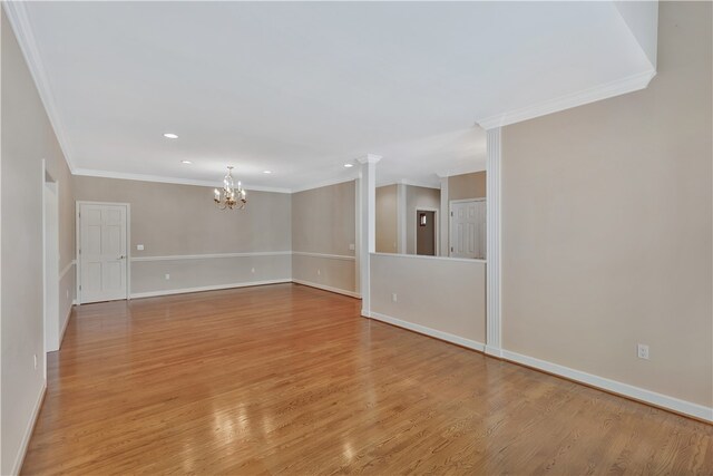 unfurnished room featuring ornamental molding, light wood-type flooring, decorative columns, and a notable chandelier