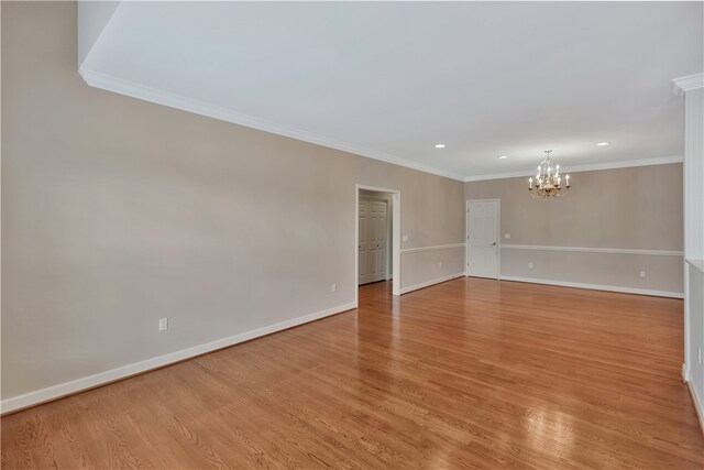 empty room with light hardwood / wood-style floors, ornamental molding, and an inviting chandelier