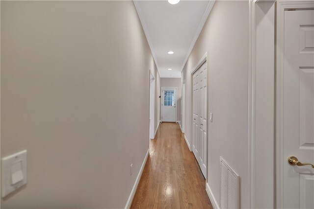 hallway with light hardwood / wood-style floors and ornamental molding