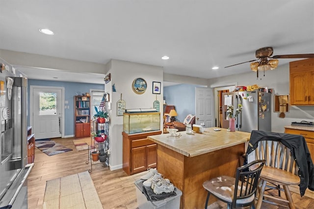 kitchen with tile countertops, light hardwood / wood-style flooring, ceiling fan, a kitchen island, and stainless steel refrigerator