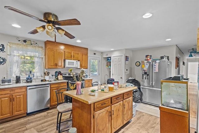 kitchen featuring a breakfast bar, a center island, appliances with stainless steel finishes, and light hardwood / wood-style flooring