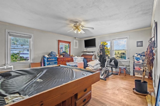 game room with ceiling fan, light hardwood / wood-style floors, ornamental molding, and a wealth of natural light