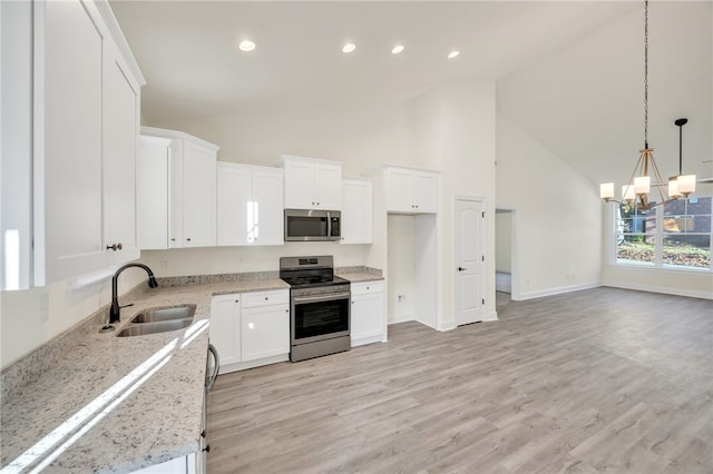 kitchen featuring light stone countertops, white cabinetry, stainless steel appliances, and high vaulted ceiling