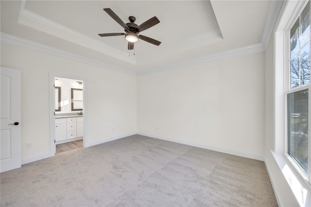 unfurnished bedroom featuring a raised ceiling, ensuite bathroom, ceiling fan, and ornamental molding