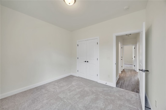 unfurnished bedroom with light carpet and a closet