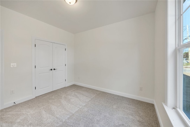 unfurnished bedroom featuring light carpet and a closet