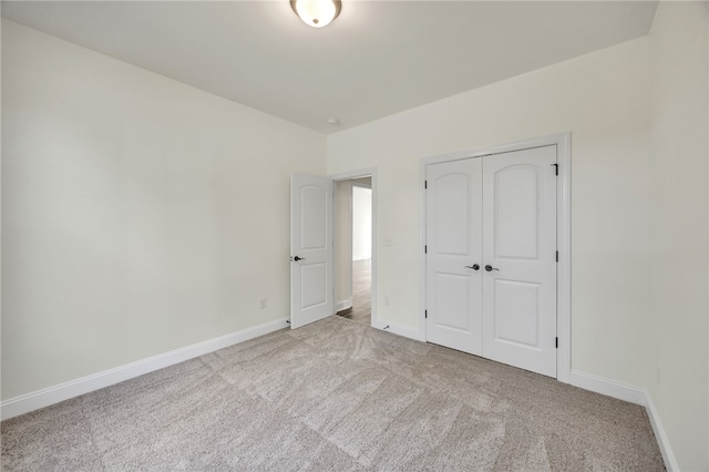 unfurnished bedroom featuring light carpet and a closet