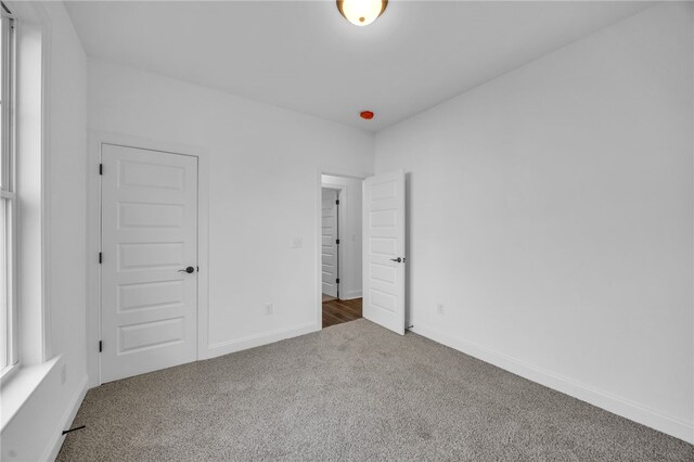 unfurnished bedroom featuring dark carpet and a closet