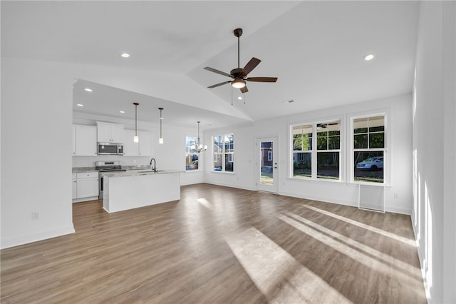 unfurnished living room featuring ceiling fan with notable chandelier, sink, light hardwood / wood-style flooring, and vaulted ceiling
