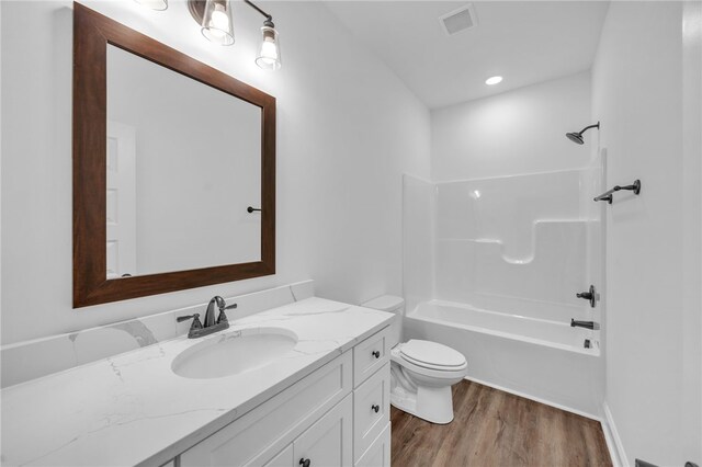 full bathroom featuring vanity,  shower combination, hardwood / wood-style flooring, and toilet