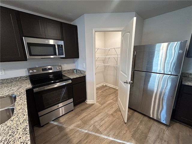 kitchen with light stone countertops, stainless steel appliances, and light wood-type flooring