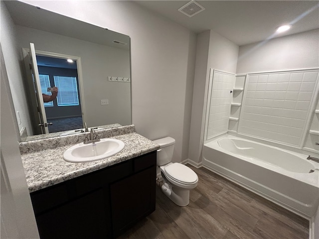 full bathroom with hardwood / wood-style floors, vanity, toilet, and shower / washtub combination