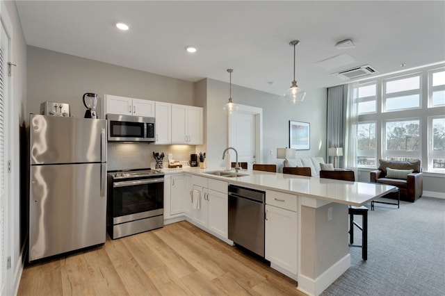 kitchen featuring decorative light fixtures, stainless steel appliances, white cabinetry, and sink