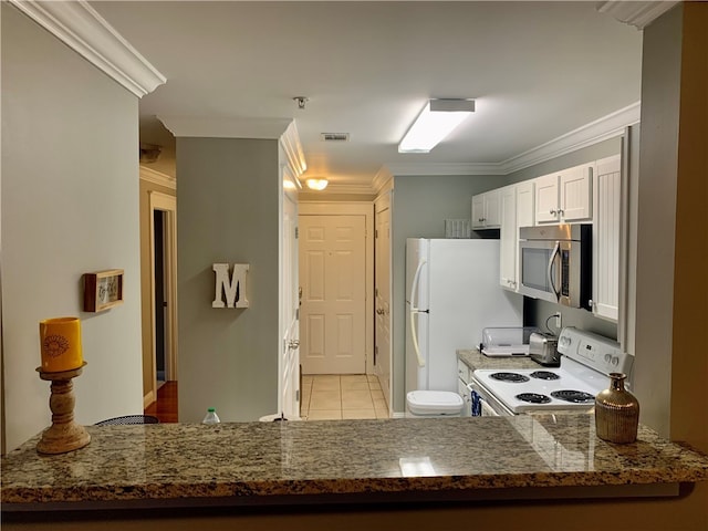 kitchen with ornamental molding, white appliances, light tile patterned floors, dark stone countertops, and white cabinets