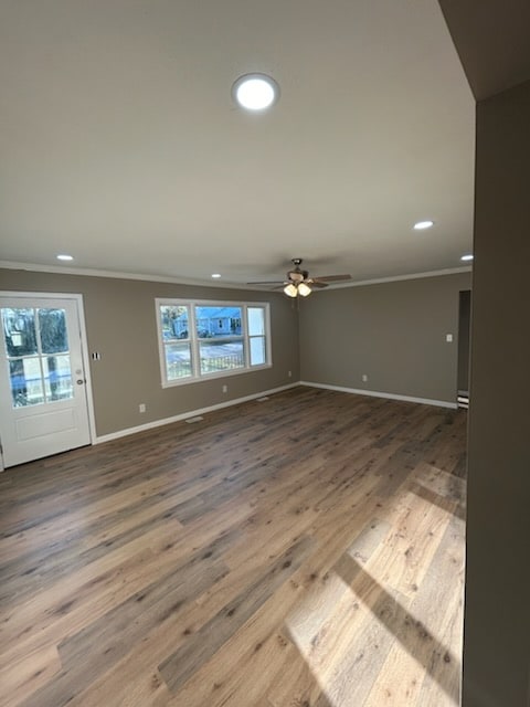 unfurnished living room featuring hardwood / wood-style flooring, ceiling fan, and ornamental molding