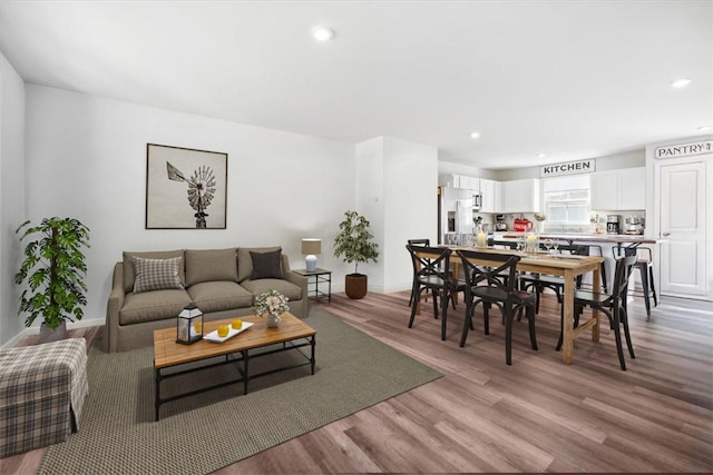 living area featuring baseboards, recessed lighting, and light wood-style floors