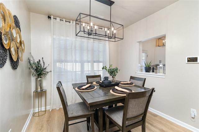 dining area featuring light wood-type flooring and a notable chandelier