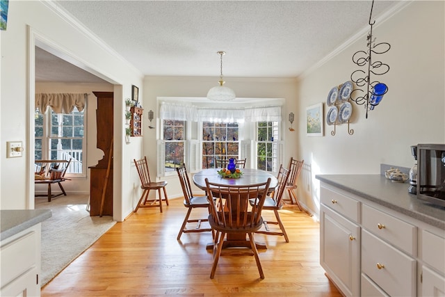 dining space with a healthy amount of sunlight, light wood-type flooring, and a textured ceiling