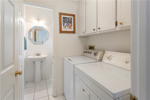 laundry area featuring washing machine and dryer, sink, light tile patterned floors, and cabinets