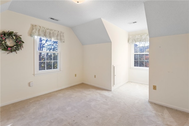 bonus room featuring light colored carpet, lofted ceiling, and a textured ceiling