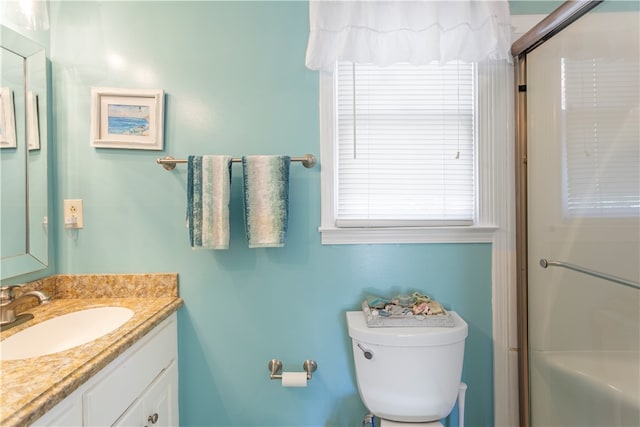 bathroom featuring toilet, vanity, and walk in shower