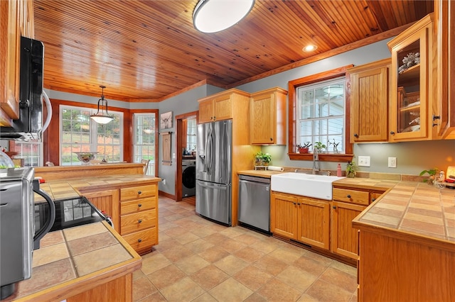 kitchen with tile countertops, washer / clothes dryer, stainless steel appliances, and hanging light fixtures