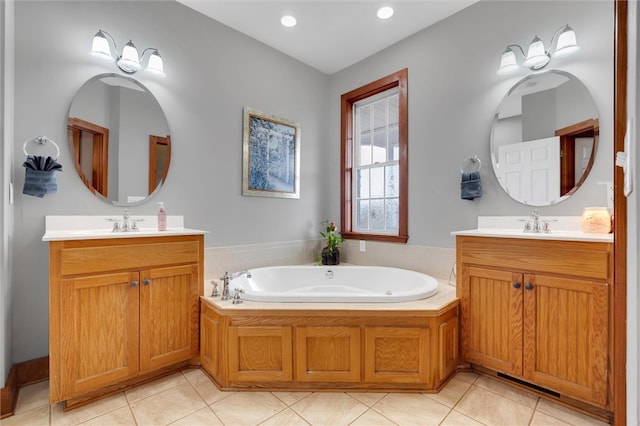 bathroom with a washtub, vanity, and tile patterned flooring