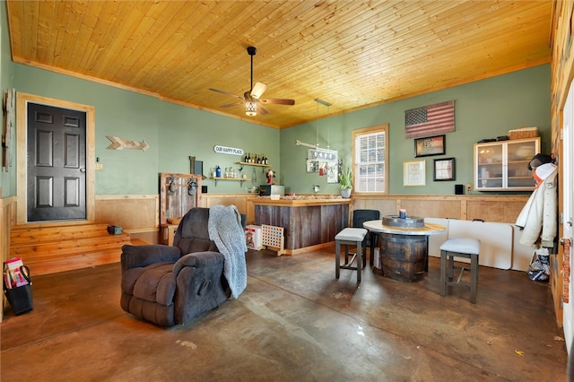 interior space with ceiling fan, wood walls, wooden ceiling, and bar area