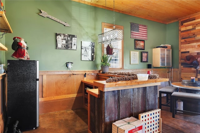 bar with hanging light fixtures, stainless steel fridge, wooden walls, and wood ceiling