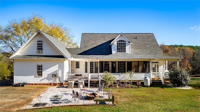 back of property featuring cooling unit, an outdoor fire pit, a patio area, a sunroom, and a lawn