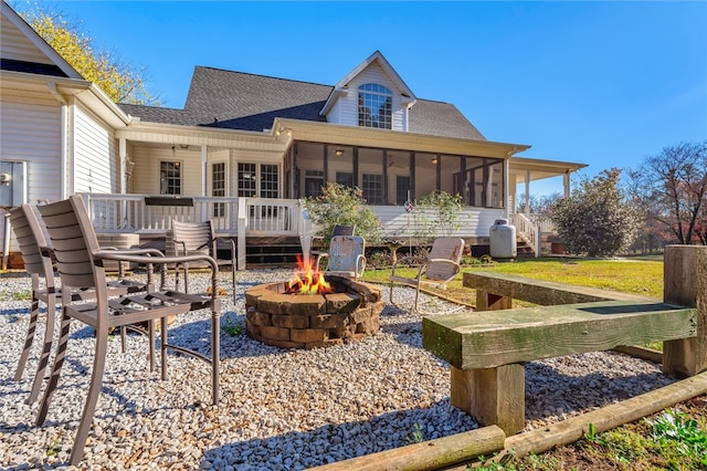 rear view of property featuring a patio area, a sunroom, and a fire pit