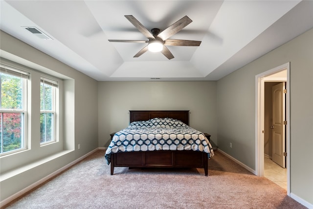 carpeted bedroom featuring a raised ceiling and ceiling fan