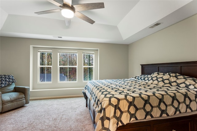 carpeted bedroom featuring ceiling fan and a raised ceiling