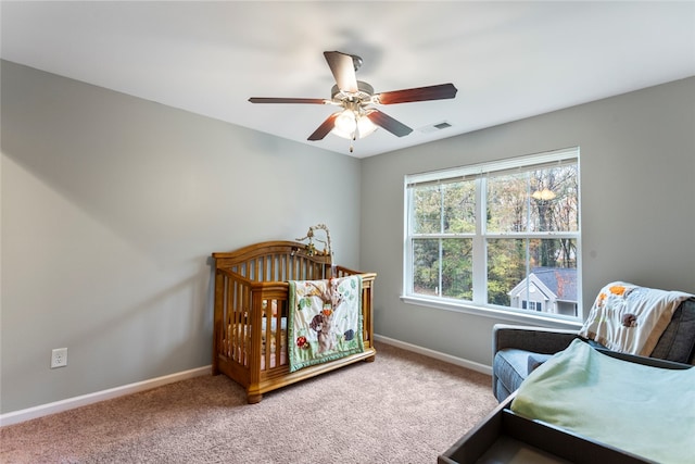 bedroom with carpet flooring, ceiling fan, and a nursery area