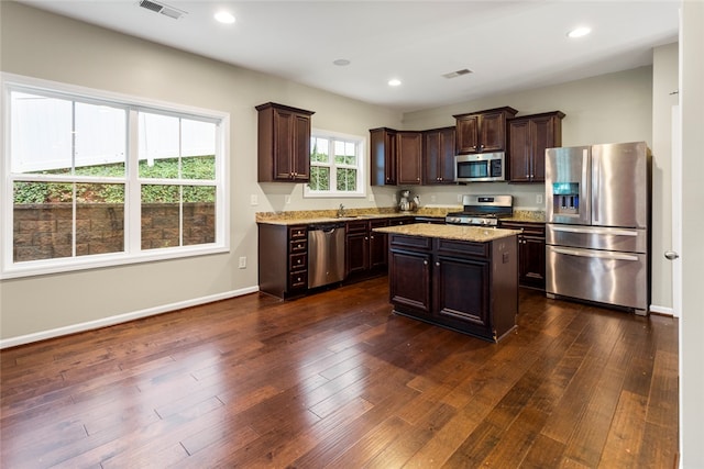 kitchen with dark brown cabinetry, a center island, dark wood-type flooring, and appliances with stainless steel finishes