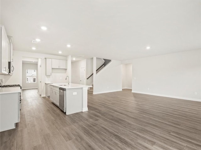 kitchen with sink, a center island with sink, light wood-type flooring, appliances with stainless steel finishes, and white cabinets