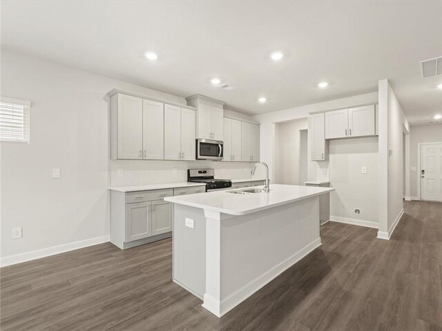 kitchen featuring an island with sink, appliances with stainless steel finishes, sink, and dark wood-type flooring