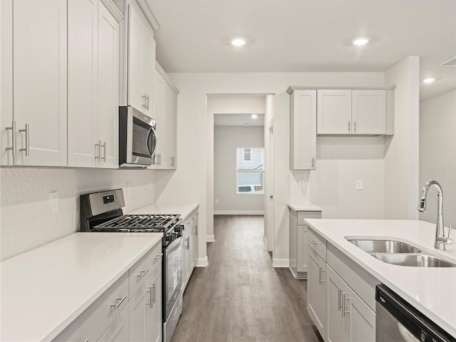 kitchen with sink, wood-type flooring, stainless steel appliances, and white cabinets