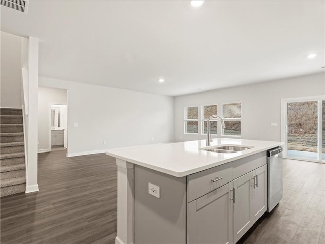 kitchen with dark hardwood / wood-style flooring, sink, dishwasher, and a kitchen island with sink