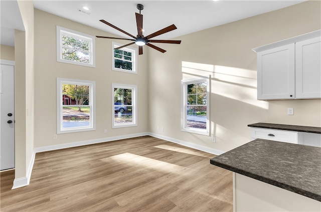 interior space with a wealth of natural light, light hardwood / wood-style flooring, white cabinets, and ceiling fan