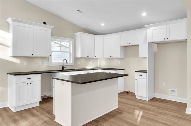 kitchen with white cabinetry, a center island, and light hardwood / wood-style floors