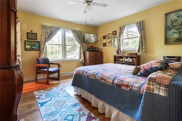 bedroom featuring multiple windows, ceiling fan, and hardwood / wood-style floors